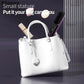 White handbag with beauty products including a rechargeable hair straightening comb inside, showcasing portable styling tools.